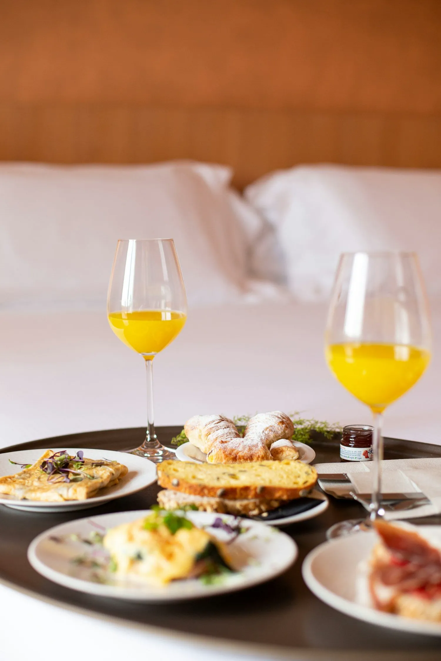 Room-service breakfast tray with juice and pastries on a hotel bed
