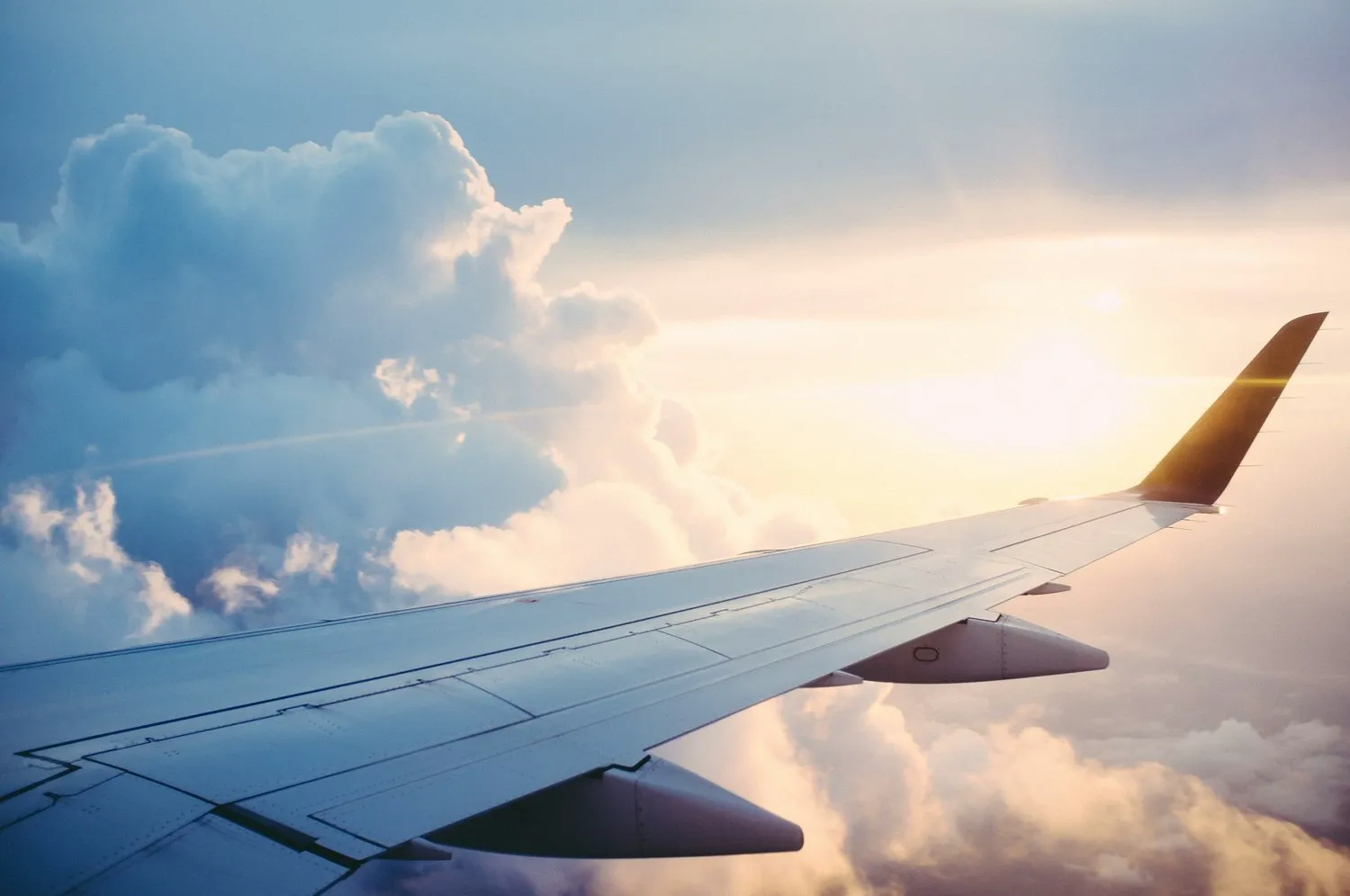 Airplane wing above the clouds at sunset